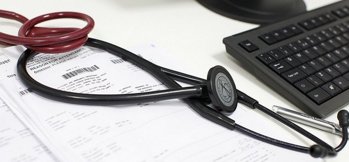 Stethoscope on a desk with medical notes and a keyboard
