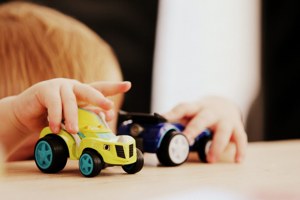 A child's hands playing with toy cars