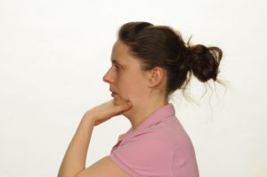 Photograph of person holding their chin and pushing back into their face towards their neck