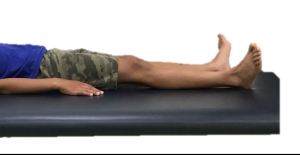 Photograph of person laid on their back with both legs outstretched and squeezing their bottom